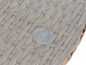 Detail okrúhleho ratanového stola so sklenenou doskou.