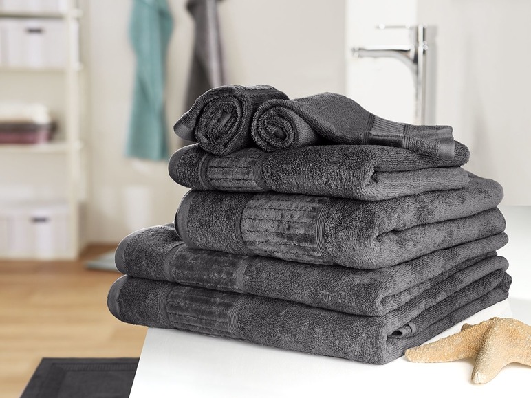 Kôpka tmavosivých uterákov v kúpeľni.