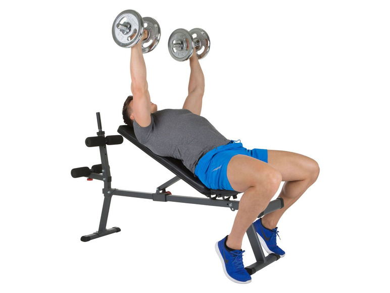 Muž robí bench press s činkami na lavičke.
