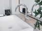 Kúpeľňa s bielou umývadlom, dvoma chrómovými batériami a dávkovačom od Le Bain.