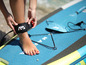 Žena si pripája leash na nohu na sup paddleboard značky Aqua Marina.