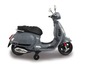 Sivá elektrická Vespa pre deti s pomocnými kolieskami.