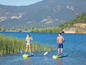 Dvaja ľudia na paddleboardoch, veslujú na jazere.