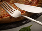 Vidlička a nôž na pizzu Echtwerk vedľa pizze.
