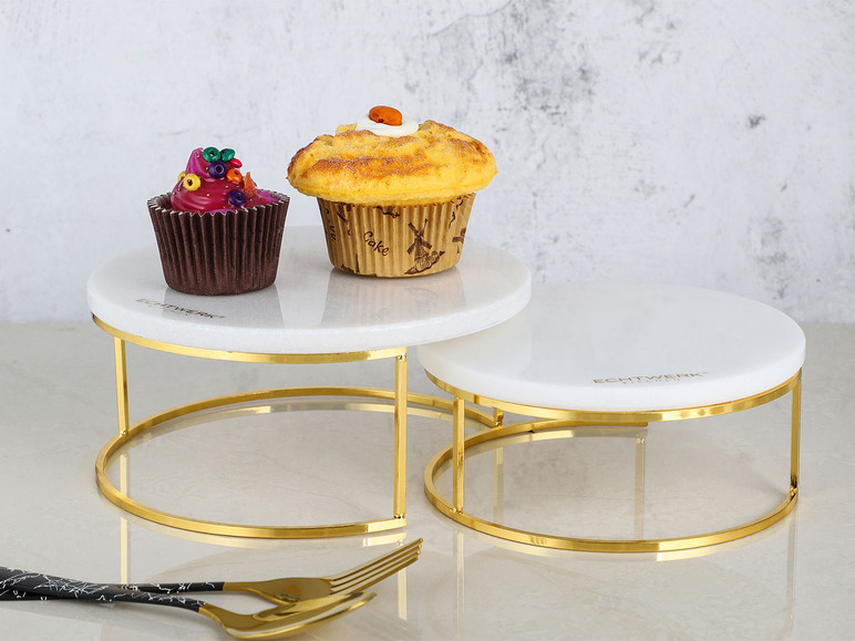 Dve okrúhle mramorové podnosy na tortu so zlatým podstavcom, zdobené cupcakes.