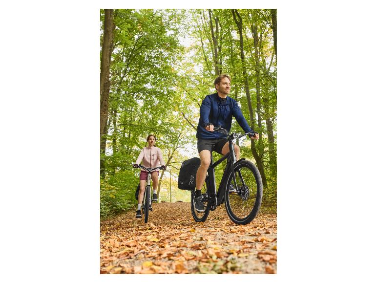 Dvaja ľudia na bicykloch na lesnej ceste pokrytej jesenným lístím.