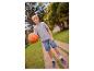 Chlapec v sivom tričku, džínsových šortkách a teniskách drží basketbalovú loptu na chodníku.