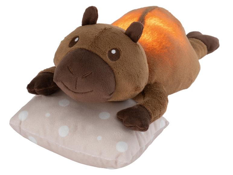 Hnedá plyšová nočná lampa kapybara na vankúši s bodkami.