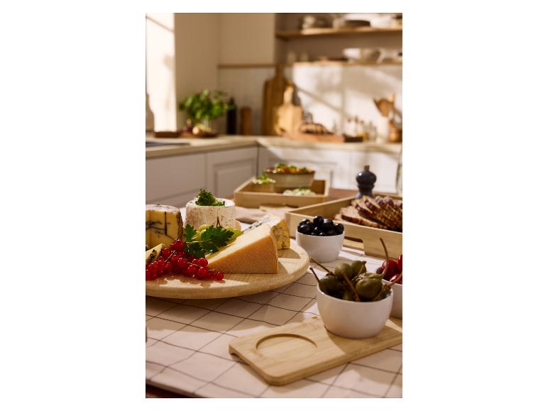 Výber syrov, bobúľ a olív na kuchynskom stole.