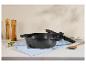Čierny hrniec s pokrievkou, mlynčeky na soľ a korenie, drevená lyžica a koreniny na kuchynskej linke.