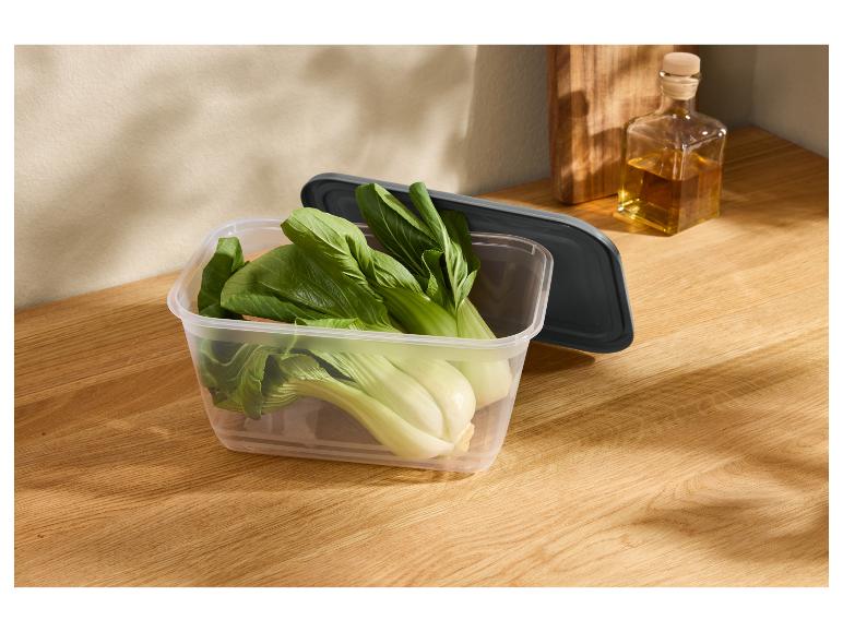 Čerstvé pak choi v priehľadnej nádobe na drevenej doske.