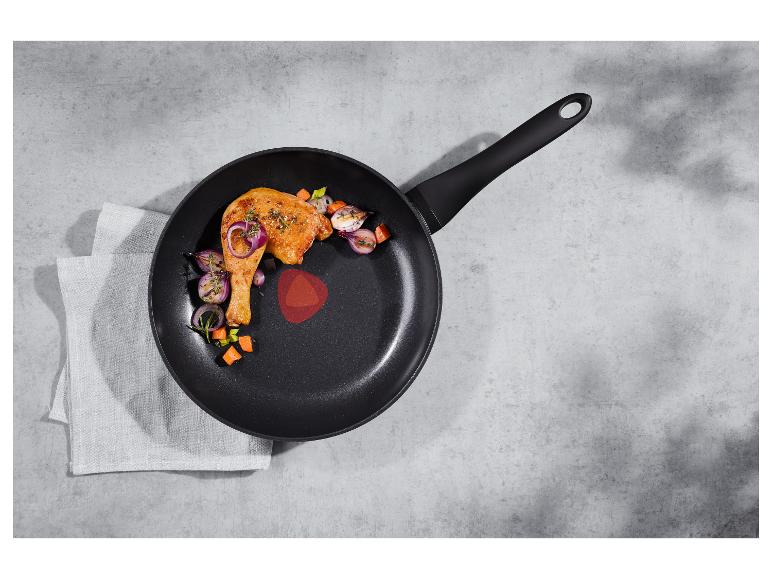 Panvica s kuracím stehnom a zeleninou na sivom pozadí s utierkou.