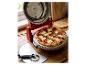 Čerstvo upečená pepperoni pizza v červenej elektrickej peci na pizzu, s krájačom na pizzu nablízku.