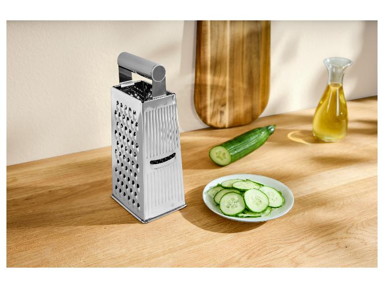 Strúhadlo na syr, uhorka a nakrájaná uhorka na drevenej doske.