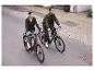 Dvaja ľudia idú na bicykloch po mestskej ceste na dvoch elektrických bicykloch.