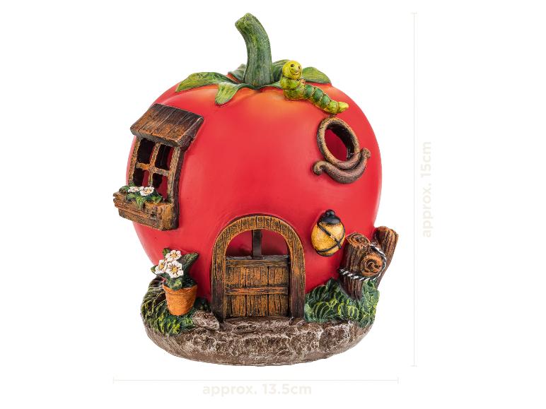 Dekoratívny domček pre víly v tvare paradajky s oknom, dverami, kvetmi a húsenicou navrchu.