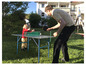 Dospelý a dieťa hrajú stolný tenis v záhrade.