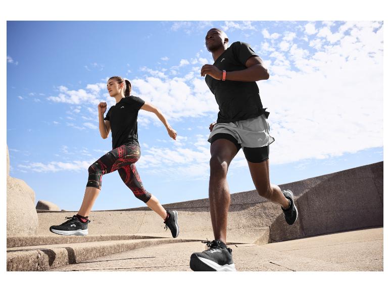 Dvaja ľudia bežiaci vonku v čiernom a sivom športovom oblečení, s fitness náramkami.
