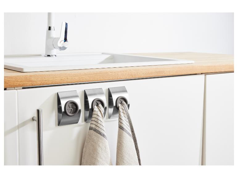 Kuchyňa s drezom, batériou a tromi nerezovými držiakmi na utierky s kuchynskými utierkami.