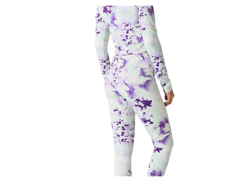 Žena v svetlozelenom a fialovom batikovanom tope s dlhým rukávom a zladených legínach.