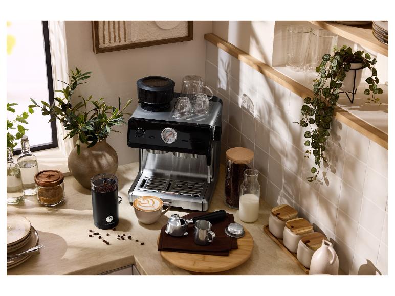 Kuchynská linka s kávovarom na espresso, mlynčekom na kávu, šálkami a kávovými zrnami.