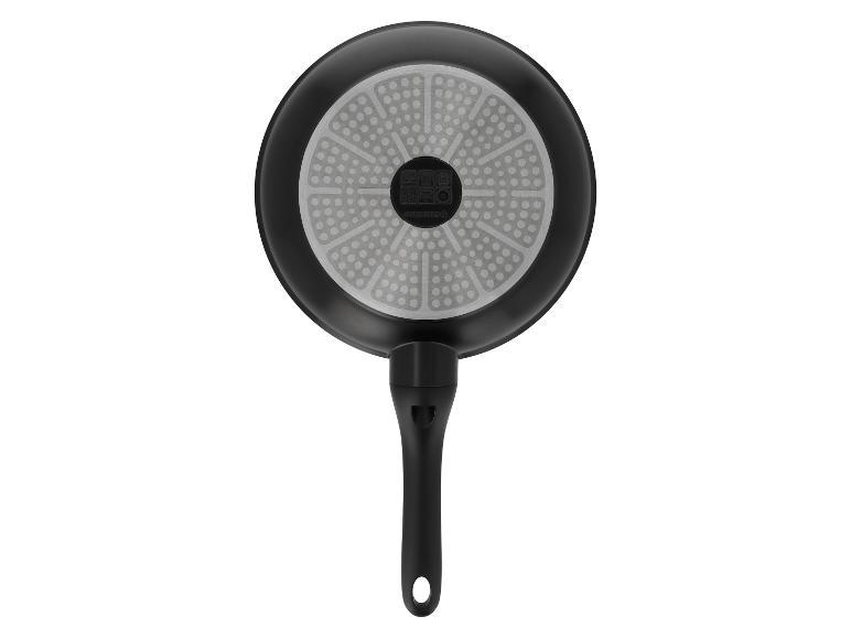 Spodná strana čiernej panvice s rukoväťou a sivým dnom s bodkovaným vzorom