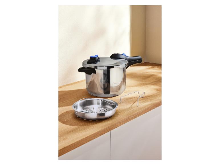 Nerezový tlakový hrniec a parný kôš na drevenej doske.