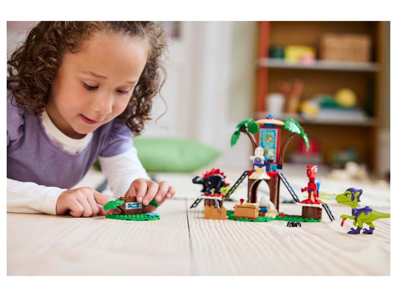Mladé dievča sa hrá so súpravou LEGO DUPLO domček na strome a figúrkami dinosaurov.