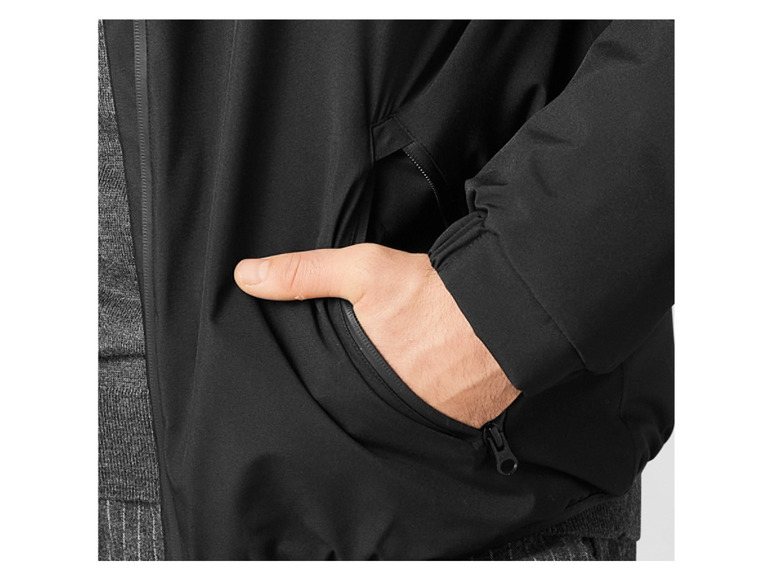 Detailný záber na čiernu bundu s vreckom na zips.