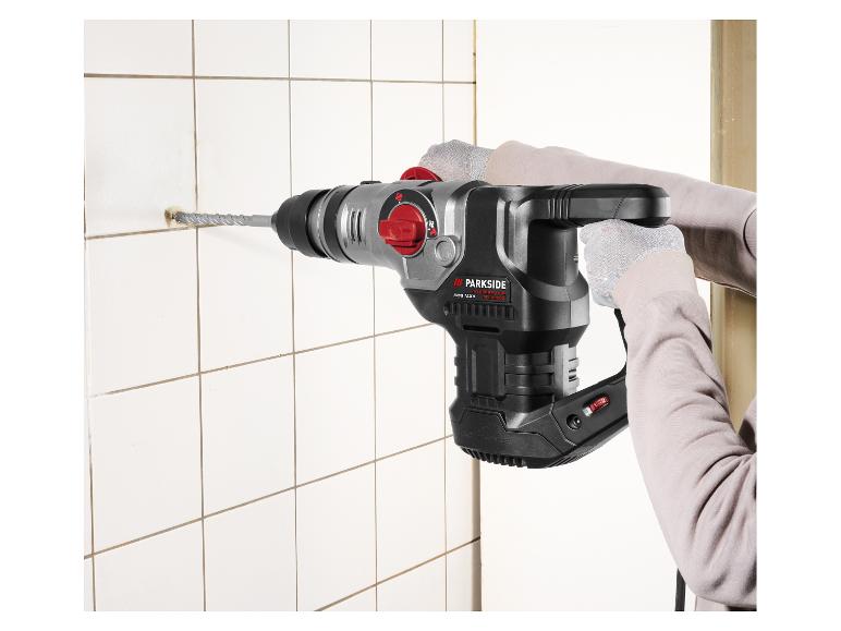 Osoba vŕta dieru do bielej dlaždice s vŕtacím kladivom Parkside Performance SDS Max.