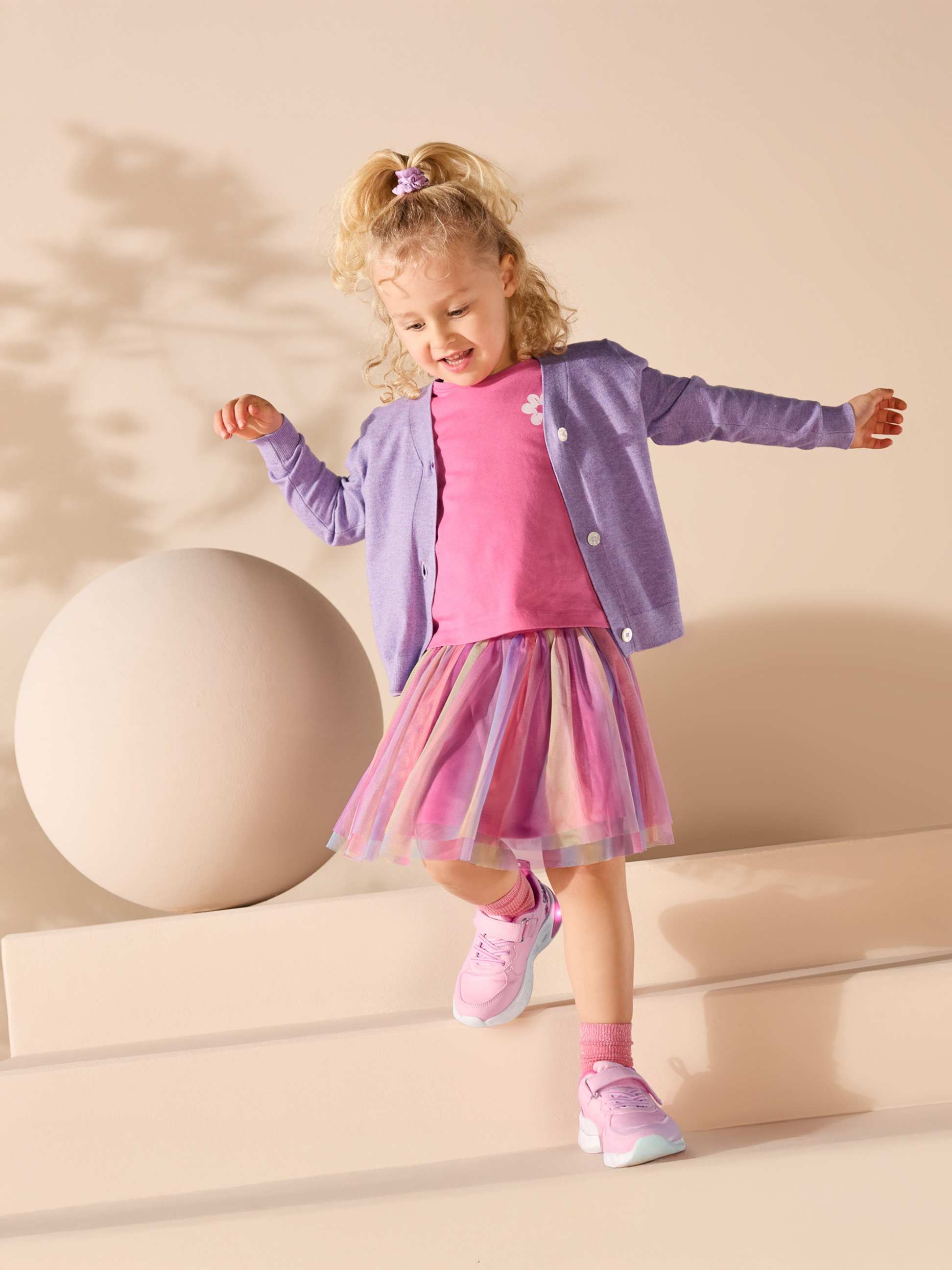 Dievčatko v ružovom tričku, fialovom kardigáne a farebnej tylovej sukni.