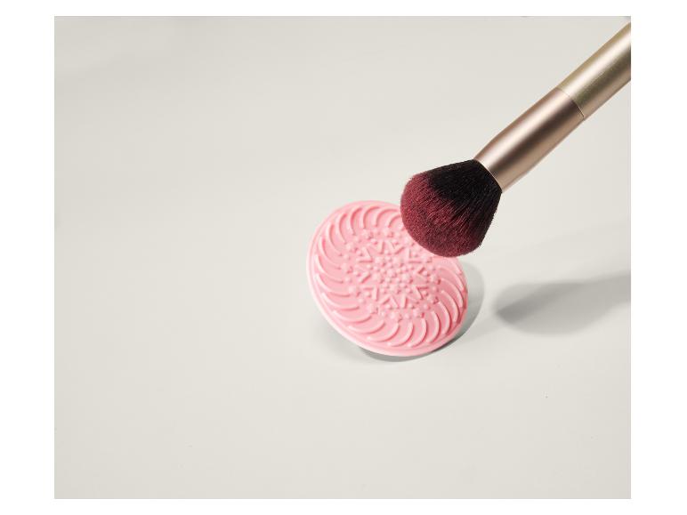 Ružová podložka na čistenie make-up štetcov s make-up štetcom.