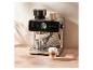 Espresso kávovar s integrovaným mlynčekom, kanvičkou na mlieko a latte kávou na drevenom stole.