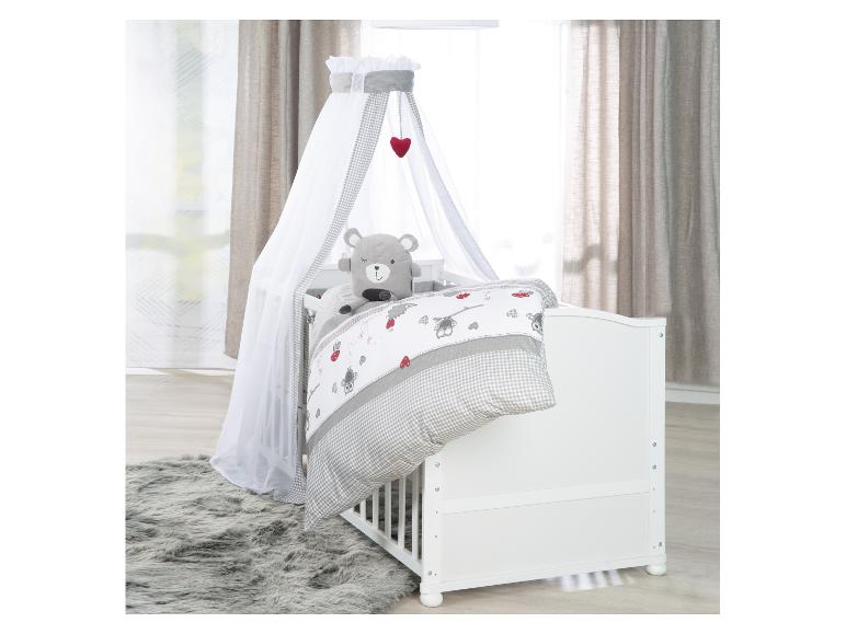 Biela detská postieľka s baldachýnom, sivou károvanou posteľnou bielizňou a plyšovým medvedíkom.