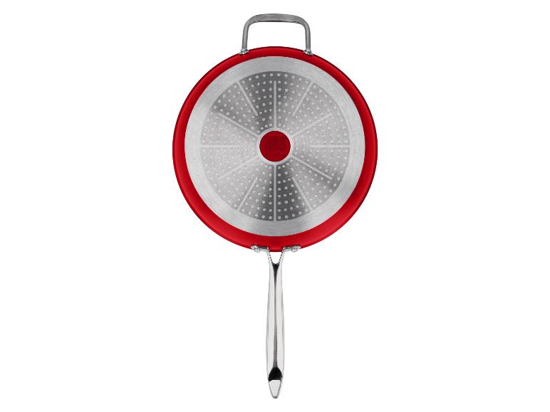 Dno červenej panvice so striebornou indukčnou základňou a kovovou rukoväťou.