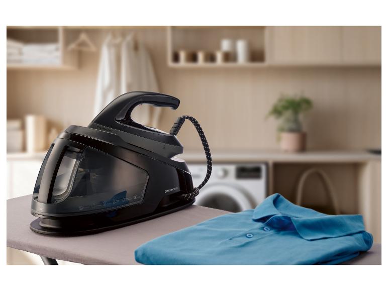 Parná žehliaca stanica na žehliacej doske so zloženou modrou košeľou.