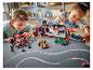 Dve deti sa hrajú so súpravami LEGO Speed Champions, vrátane prepravného kamiónu a pretekárskych áut.