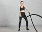 Žena v športovom oblečení používa battle rope počas tréningu.