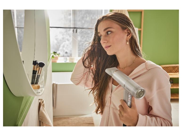 Žena suší vlasy fénom SensCare v kúpeľni.