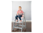 Dievča sedí na šedej vysoké stoličke Stokke Tripp Trapp.