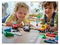 Dve deti sa hrajú s pretekárskymi autami LEGO Duplo na podlahe.
