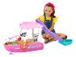 Usmievajúce sa dievča sa hrá s ružovou hračkárskou loďou Barbie, so šmýkačkou a doplnkami.