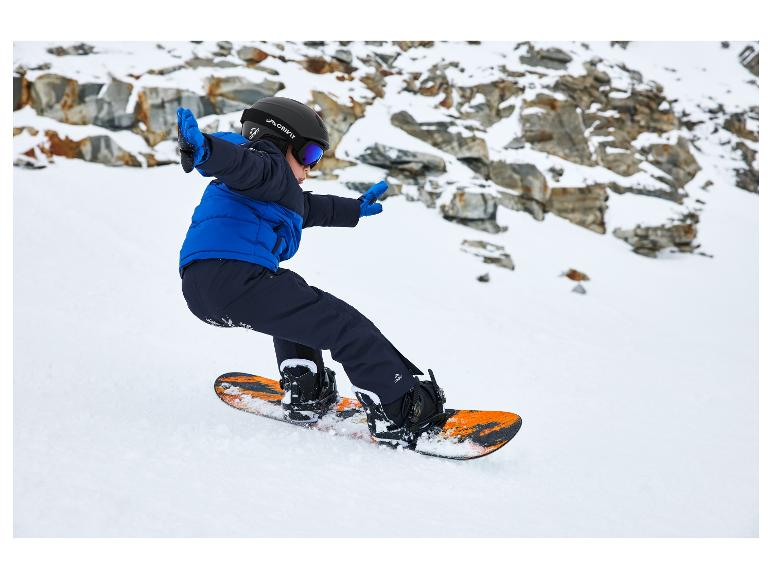 Dieťa snowboardista nosí prilbu Crivit, okuliare a modrú bundu.