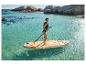 Žena v plavkách a záchrannej veste na paddleboarde v tyrkysovej vode so skalami v pozadí.