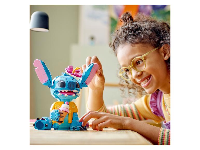 Usmievajúce sa dieťa sa hrá s figúrkou LEGO Stitch držiacej zmrzlinu.