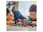 Dvaja ľudia sa hrajú so súpravou LEGO Speed Champions, pretekárskym autom a pit stopom.