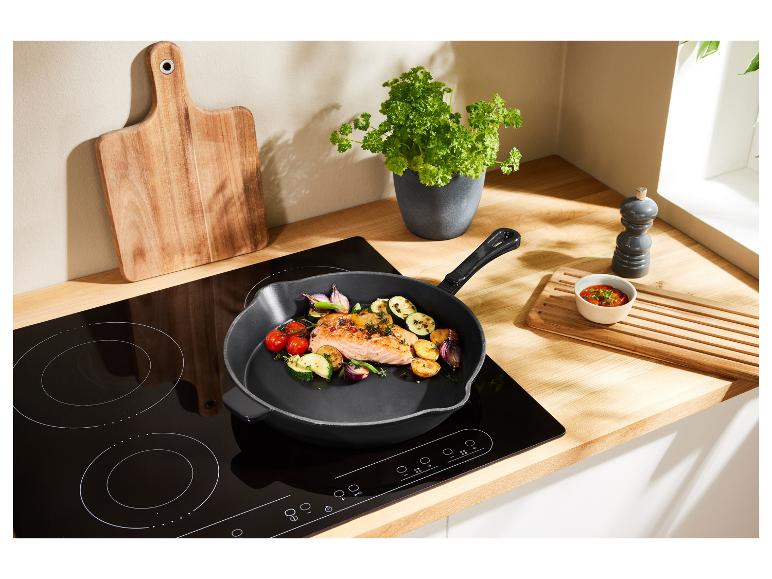 Čierna panvica s lososom a zeleninou na indukčnej varnej doske.