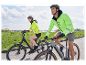 Dvaja cyklisti v cyklistickom oblečení Decathlon idú na elektrobicykloch.