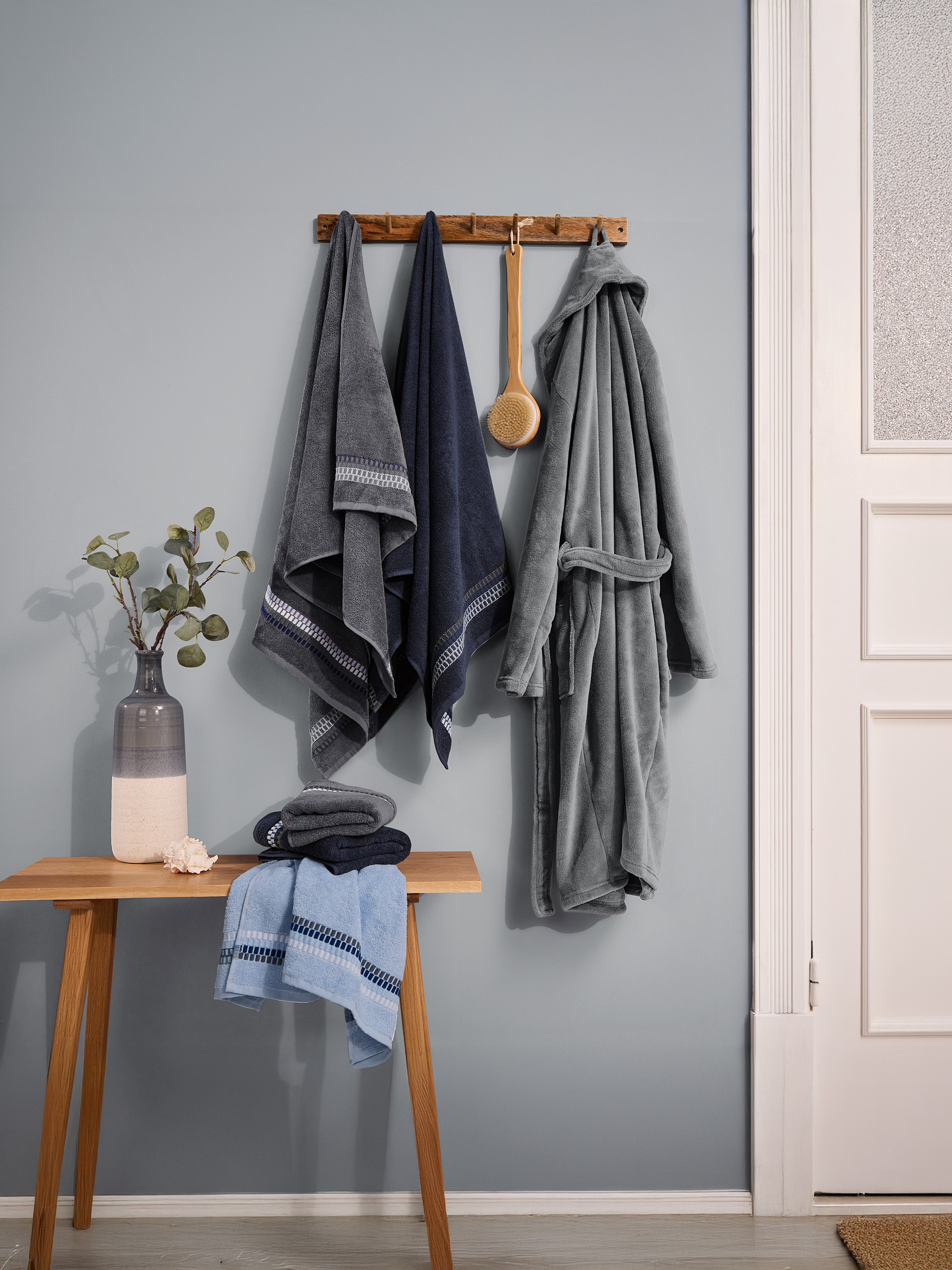 Uteráky a župan v modrých a sivých odtieňoch, visiace na stene.