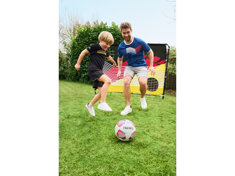 Otec a syn hrajú futbal v záhrade s futbalovou loptou France a bránkou.